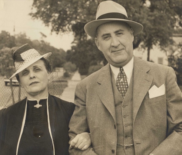 Ruth and Milton P. Levy Sr. photographed outdoors arm in arm, both in hats, he in a three-piece suit.