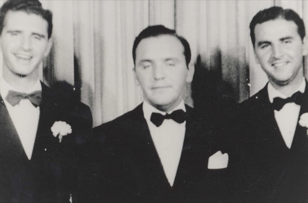 The three Levy brothers as grown men in dinner jackets and bow ties, two of them wearing carnations.
