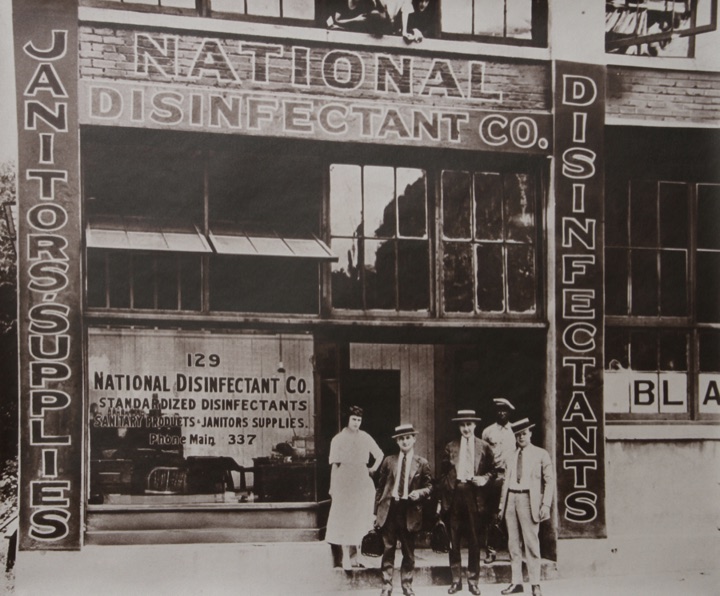 The National Disinfectant Company storefront at 129, photographed around 1918, with four members of staff standing on the step.
